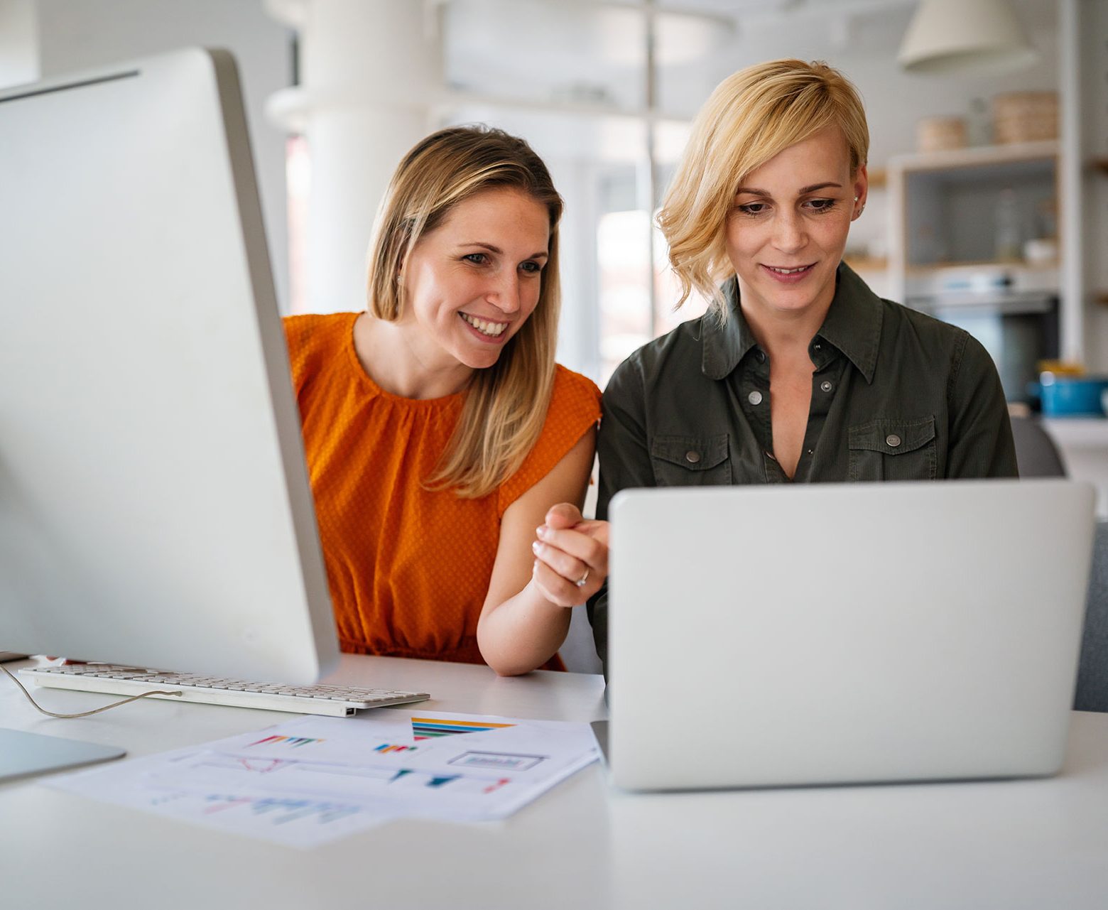 2 vrouwen achter een laptop en een desktop