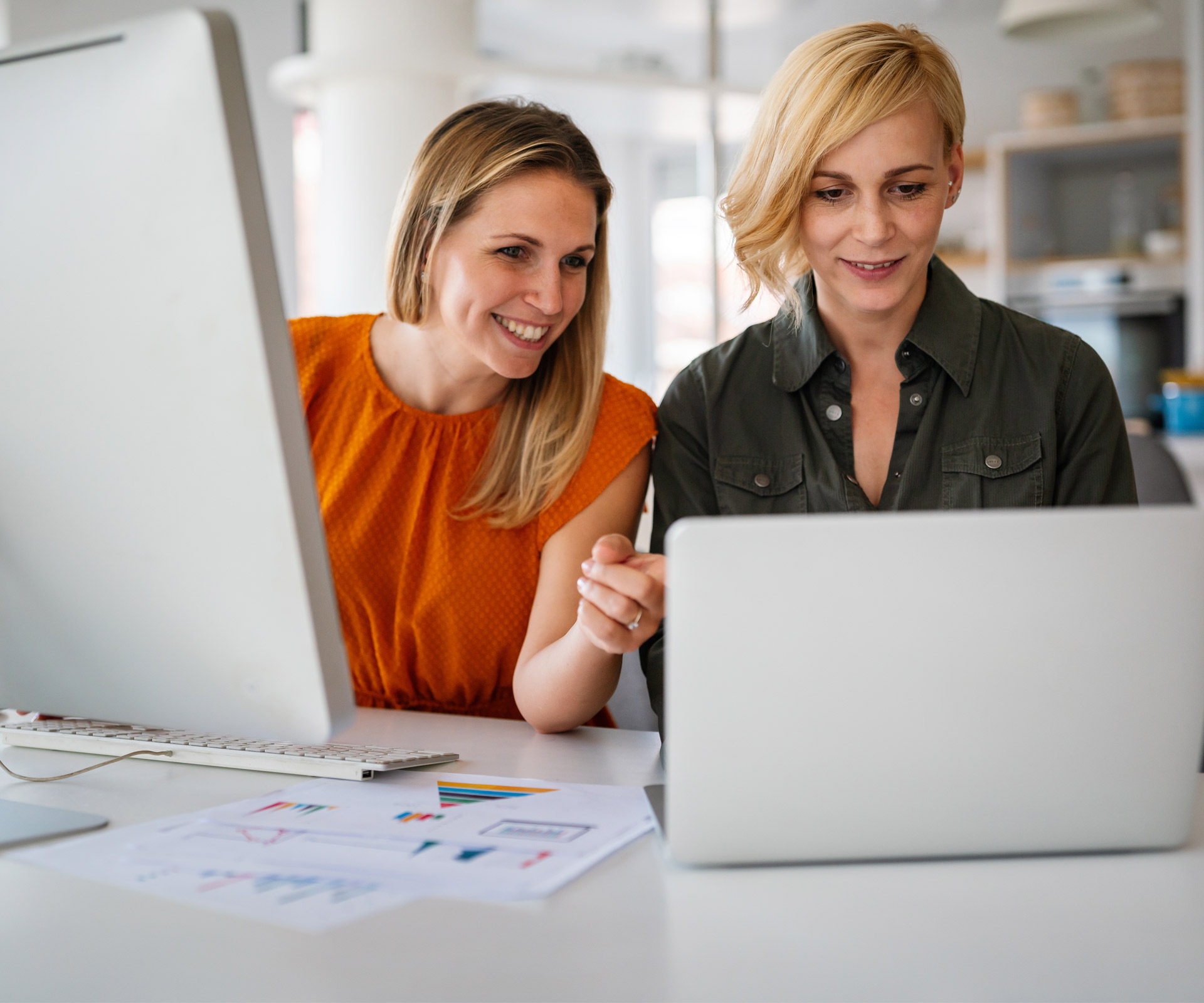 twee vrouwen achter een laptop en een desktop