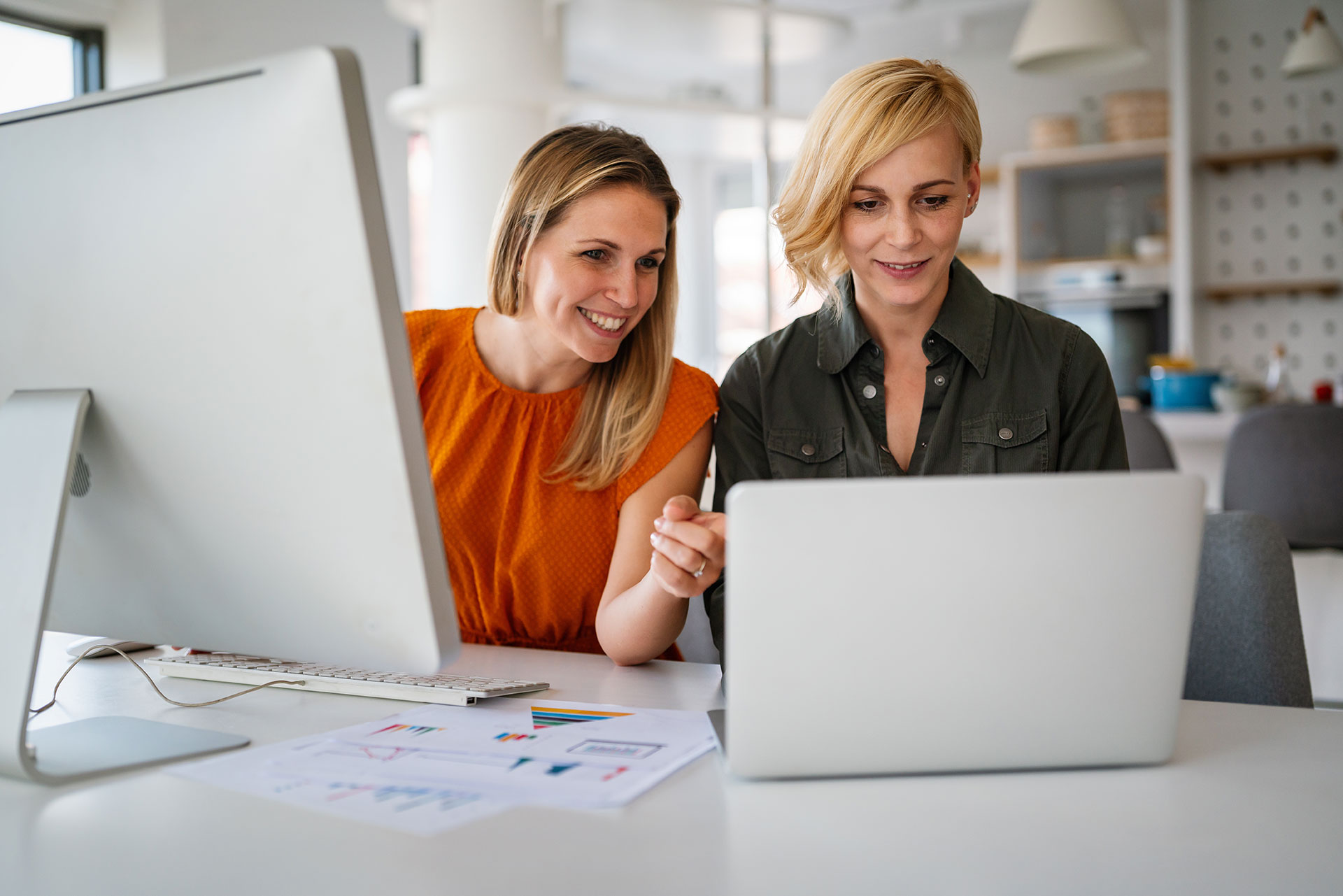 2 vrouwen achter een laptop en een desktop