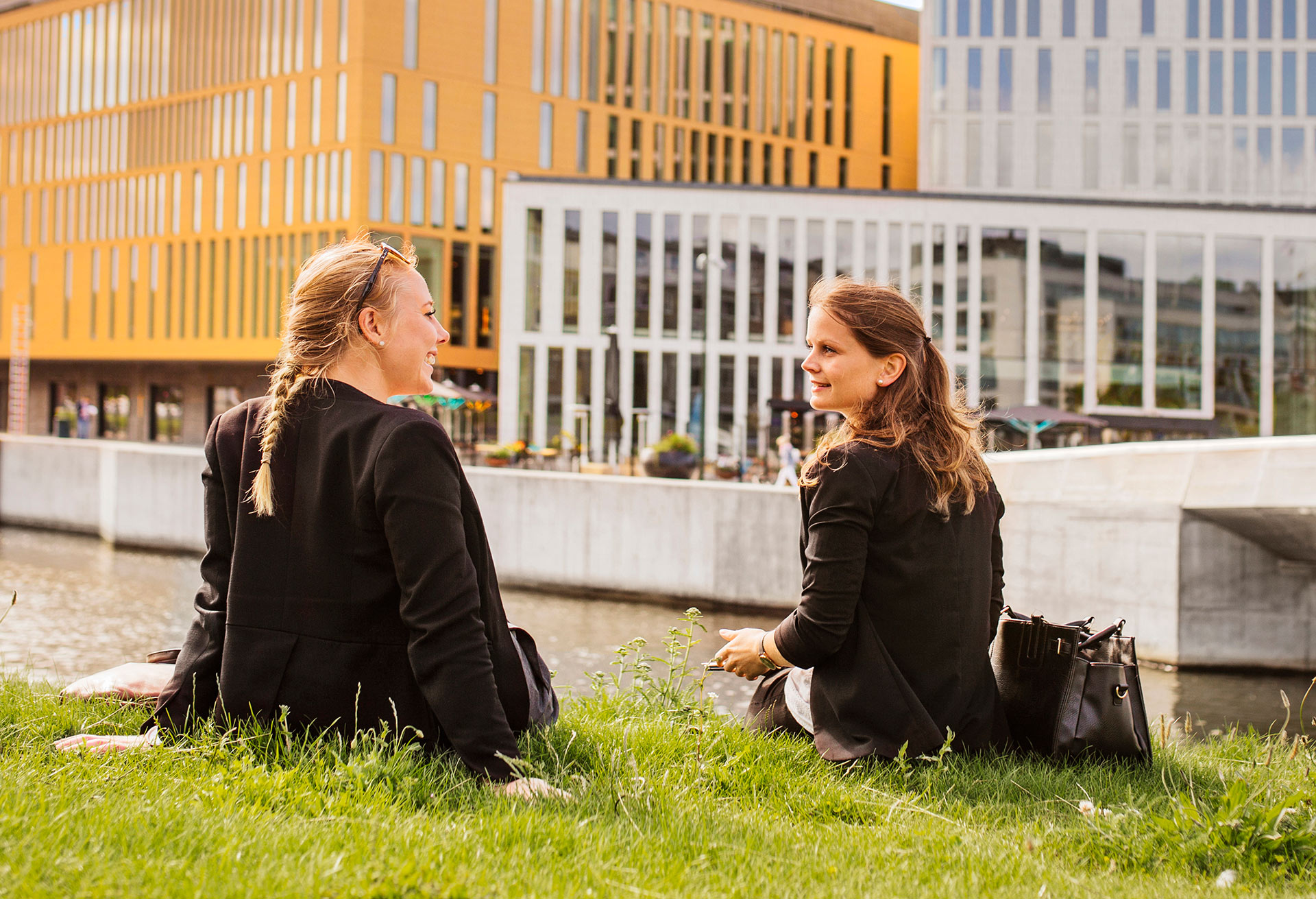 twee vrouwen zitten op het gras aan water