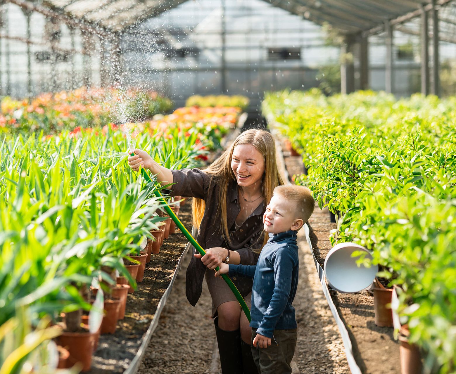 vrouw en kind sproeien in serre